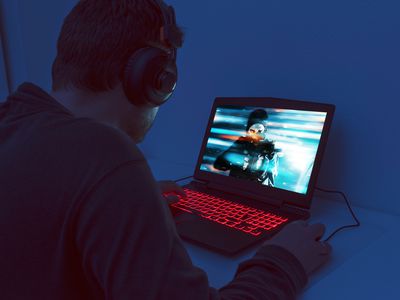 A man at a desk looking at a gaming laptop. 