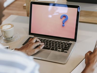 A person working on a laptop with a blue question mark on the screen