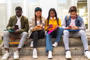 A group of people sitting and playing games on their phones.