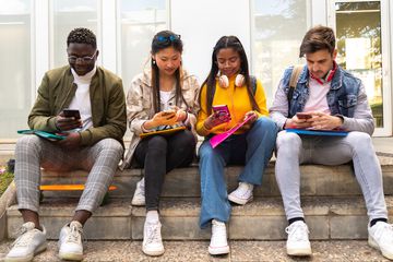 A group of people sitting and playing games on their phones.