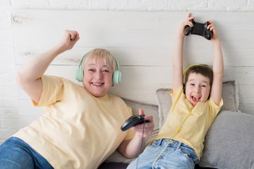 A parent and child gaming and wearing headphones. 