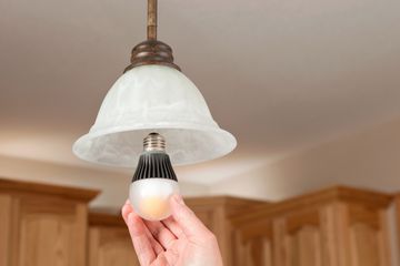 Hand installing smart light bulb into light fixture