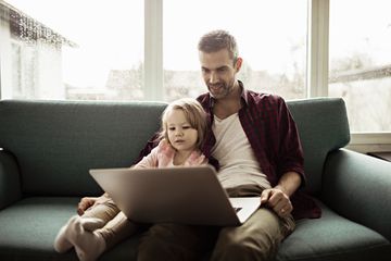 Man and young girl watching laptop on couch