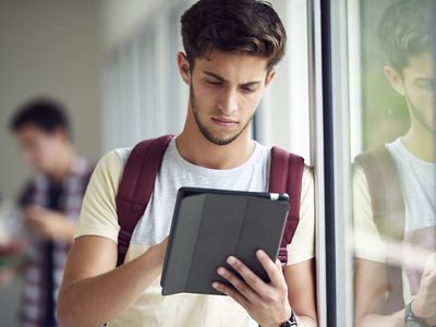 Student standing by window using tablet device