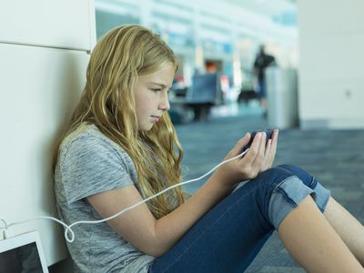 Traveler looking at a phone while it's charging in an airport terminal.