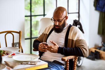 A man sitting in a chair looking at his phone carefully