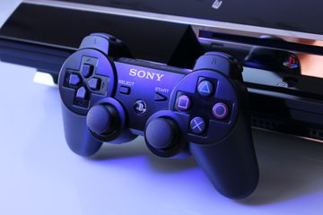 A PlayStation controller leaned on the the PS console.