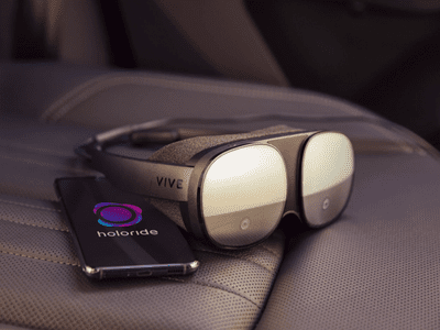 The HTC Vive Flow and a smartphone displaying the holoride logo sitting on an automobile passenger seat. 